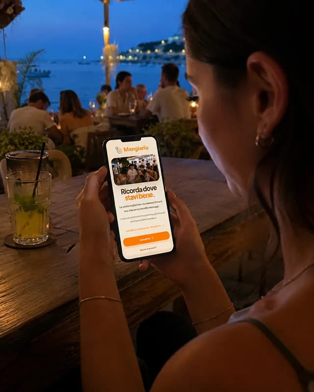Una persona usa Mangiario dal telefono durante una serata al mare
